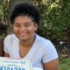 Smiling person outdoors holding pizza box